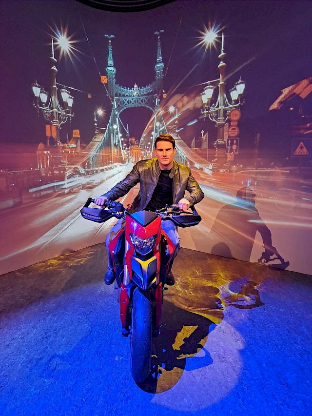La statua di cera di Tom Cruise in moto al Madame Tussauds Budapest, davanti allo scenario del Ponte della Libertà